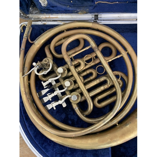 79 - A cased brass French horn (shows signs of much use, metal pitted, requires new mouthpiece, case as f... 