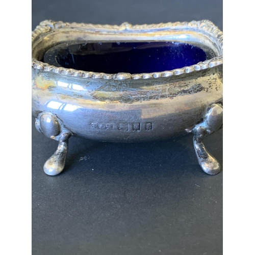 102 - A three piece hallmarked silver condiment set including open salt with blue glass liner, pepper and ... 