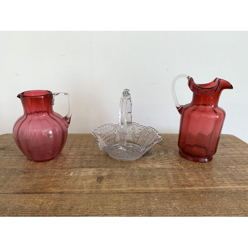 19 - Two vintage cranberry glass jugs plus a moulded glass basket