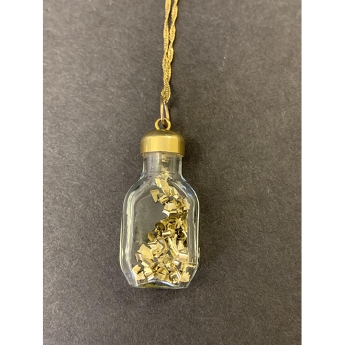 102 - A 9ct gold marked Italy glass bottle with yellow metal filings on a 9ct gold chain