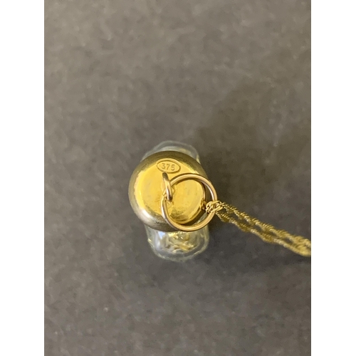 102 - A 9ct gold marked Italy glass bottle with yellow metal filings on a 9ct gold chain