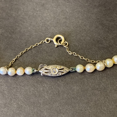 127 - A white metal clasp string of pearls, possibly marked 9c