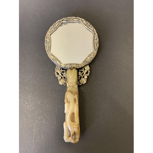 76 - A boxed Oriental hand mirror constructed from a white metal with a jade style handle and back of mir... 