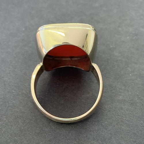 142 - A large yellow metal and carved carnelian stone ring, approx. size Y, weight approx. 13g