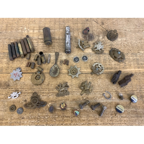 209 - A selection of WW1 and WW2 cap badges, buttons, bullet cases, shrapnel etc