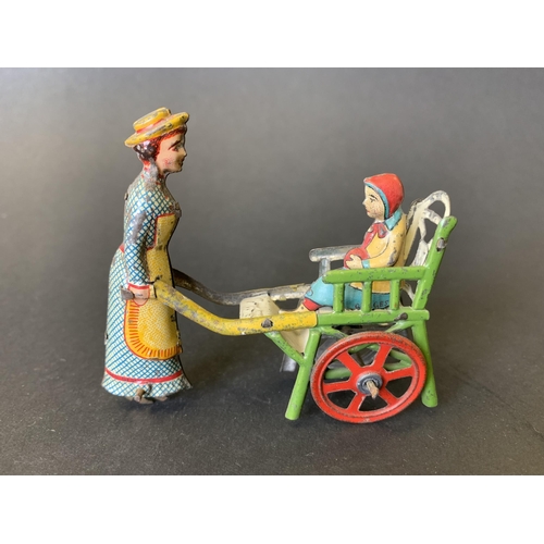 221 - An antique tin plate 'penny toy' of a lady pushing a child in a cart, by Meier of Germany, lithograp... 