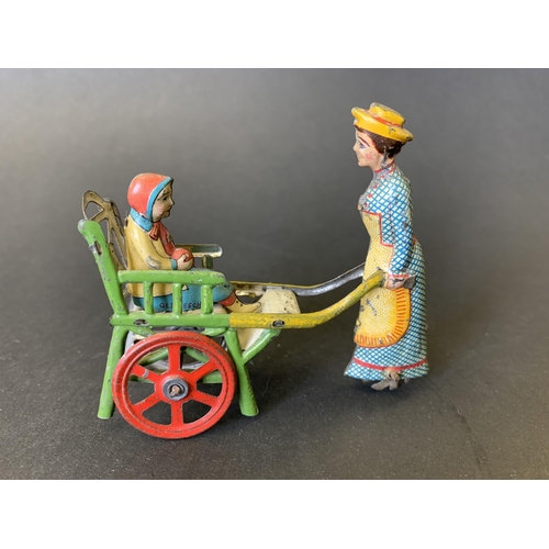 221 - An antique tin plate 'penny toy' of a lady pushing a child in a cart, by Meier of Germany, lithograp... 