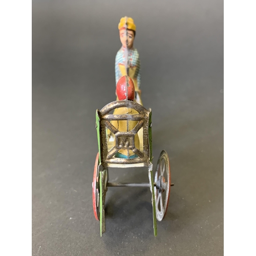 221 - An antique tin plate 'penny toy' of a lady pushing a child in a cart, by Meier of Germany, lithograp... 