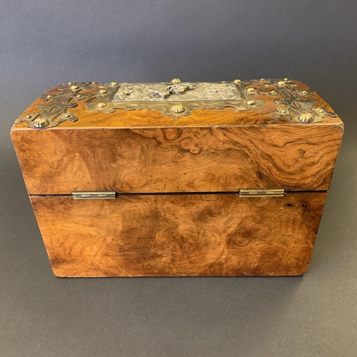 59 - An antique burr wood veneer double tea caddy, brass banded with central white metal figural scene pl... 