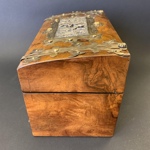 59 - An antique burr wood veneer double tea caddy, brass banded with central white metal figural scene pl... 