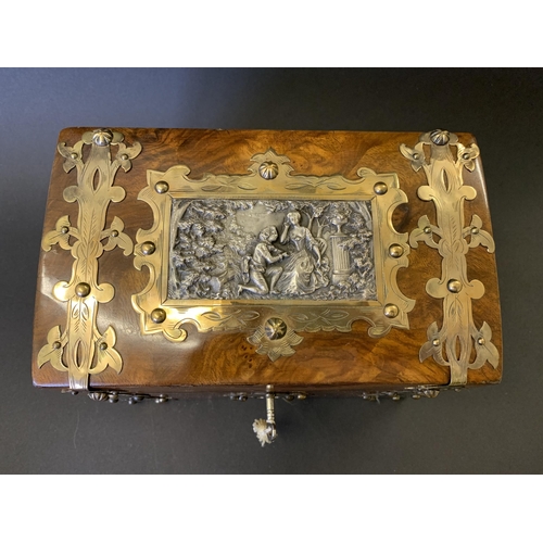 59 - An antique burr wood veneer double tea caddy, brass banded with central white metal figural scene pl... 