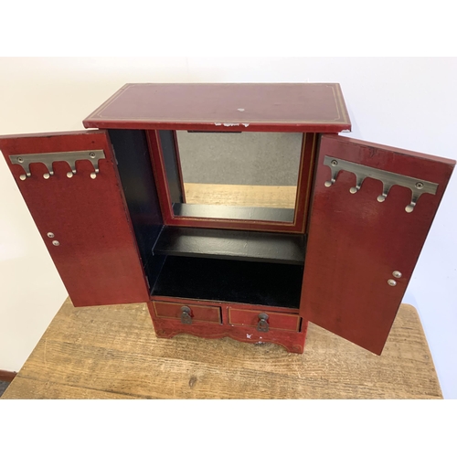 88 - A vintage Oriental style red painted jewellery cabinet with two drawers, stands 16