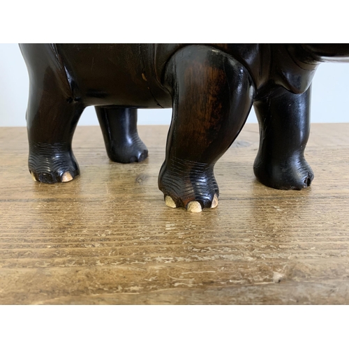 93 - An antique carved ebony rhinoceros with bone inset teeth and toenails, approx. 12 3/4