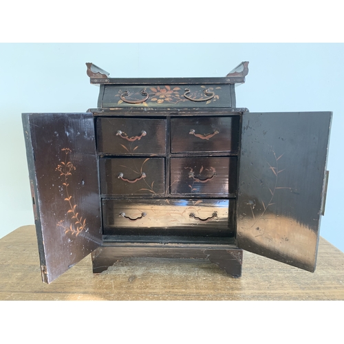 275 - A vintage Oriental small cabinet of drawers decorated with red lacquer and over gilding with scenes ... 