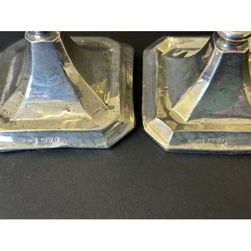 129 - A pair of hallmarked silver candlesticks with loaded bases, Chester 1919 (the base to one is missing... 