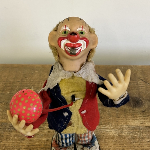 178 - A vintage Japanese battery operated tinplate and cloth juggling clown with whistle plus a small cloc... 