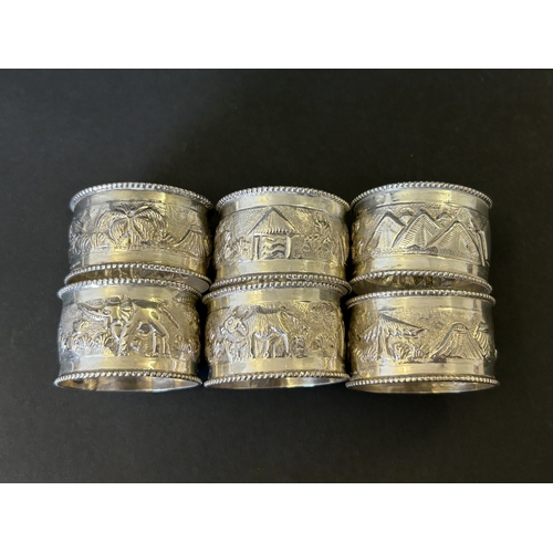 197 - A set of six sterling silver napkin rings decorated with elephants, trees and huts etc, total weight... 