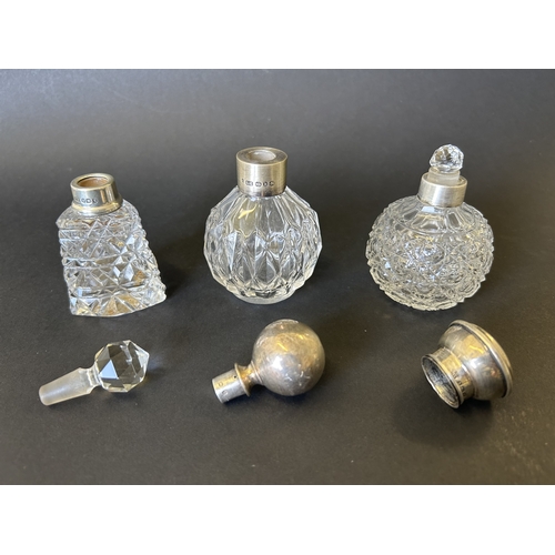 199 - Three cut glass perfume bottles with silver collars, two with hallmarked silver lids