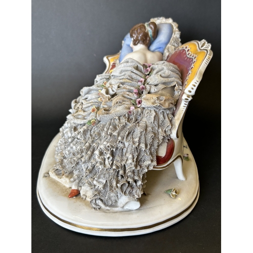 82 - A vintage Dresden porcelain lacework recumbent female figurine, bears a blue crown mark to the back,... 