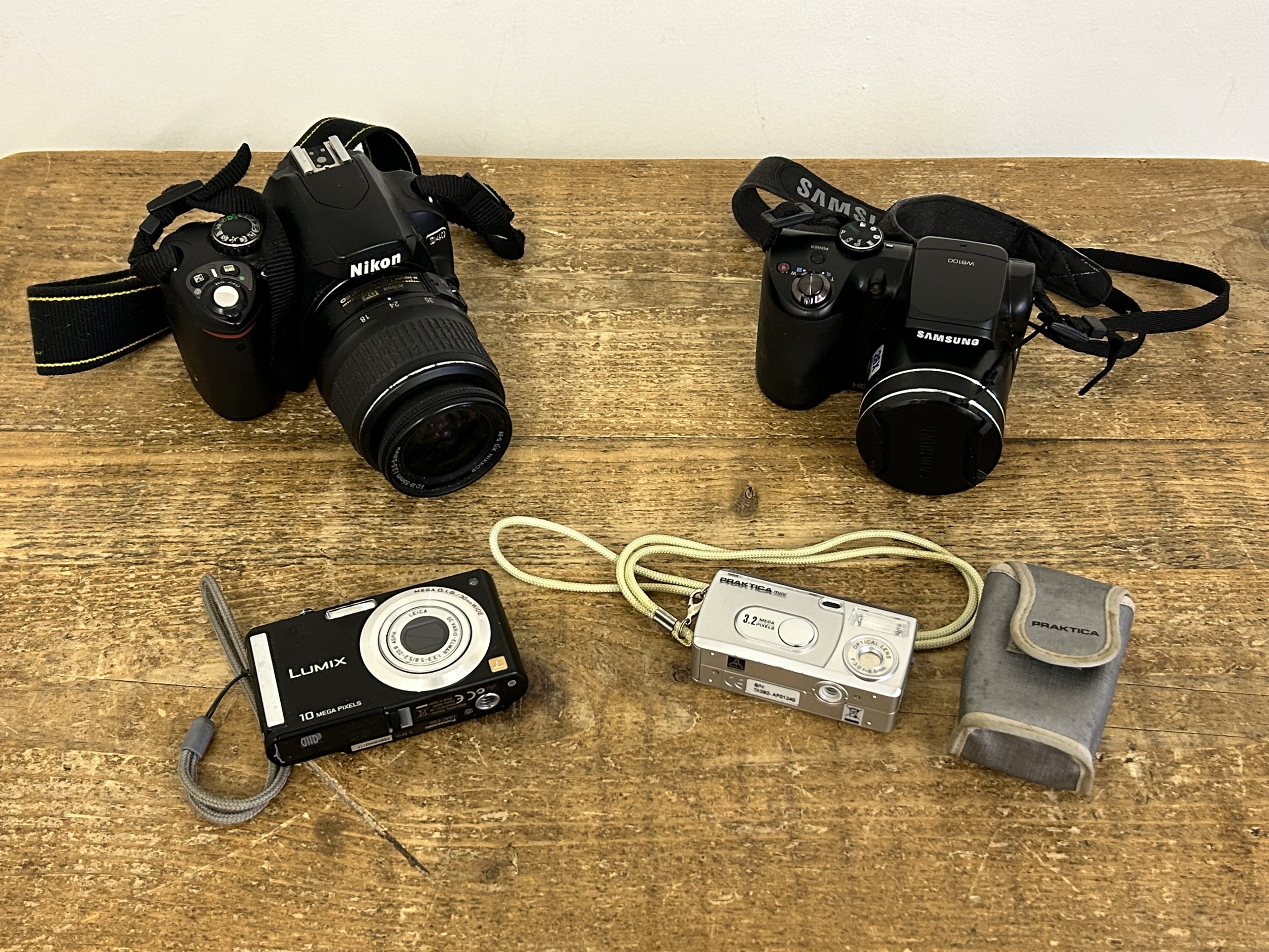 Four digital cameras to include a Nikon D40, a Samsung WB100, a Lumix ...
