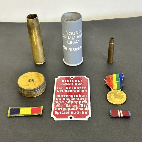 304 - A 'Dodo Design Ltd' sign with German writing, an anti dimming kit for a gas mask, a 37mm case, a 50t... 