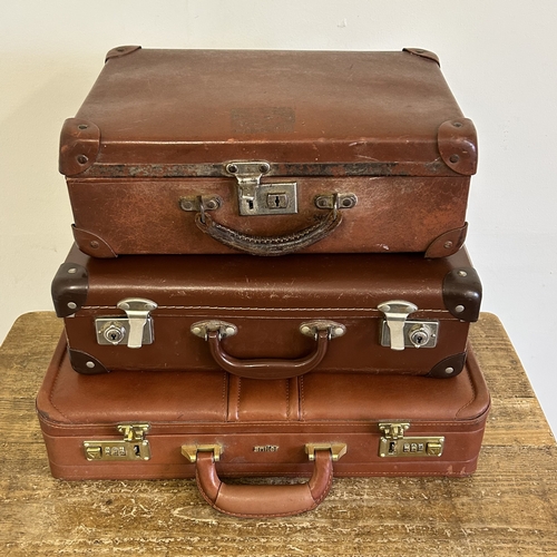 37 - Two vintage leather style small suitcases plus a leather briefcase (with age related wear)