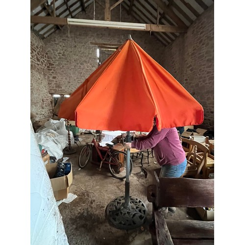 198 - Orange garden parasol. Wind up with heavy cast iron stand.