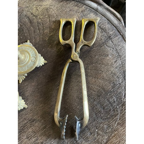 542 - Two brass candlesticks and a pair of coal tongues