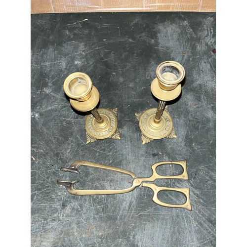 542 - Two brass candlesticks and a pair of coal tongues