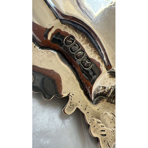 203 - A Victorian round scallop shaped salver with raised and engraved floral and leaf decoration, on 3 sp... 