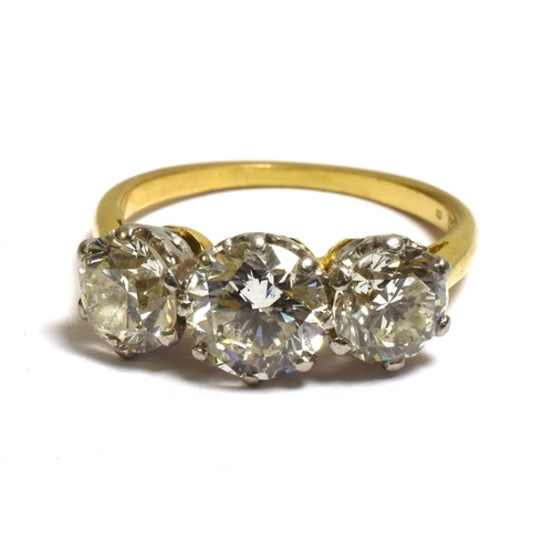 26 - A THREE STONE BRILLIANT CUT DIAMOND RING Estimated in the setting to total 3.1 carats, with diamond ... 