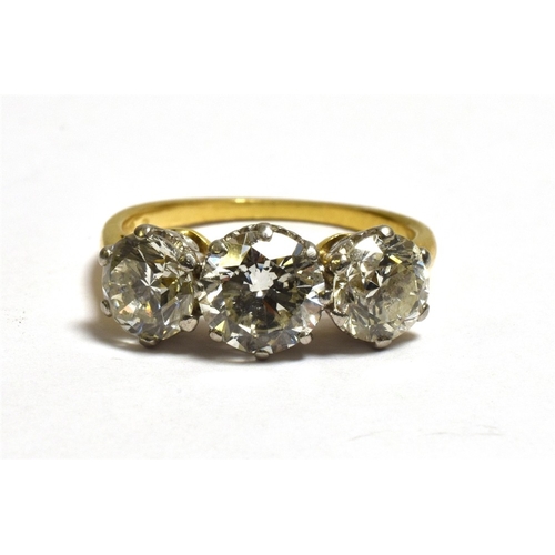 26 - A THREE STONE BRILLIANT CUT DIAMOND RING Estimated in the setting to total 3.1 carats, with diamond ... 