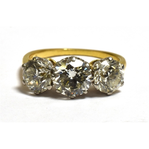 26 - A THREE STONE BRILLIANT CUT DIAMOND RING Estimated in the setting to total 3.1 carats, with diamond ... 