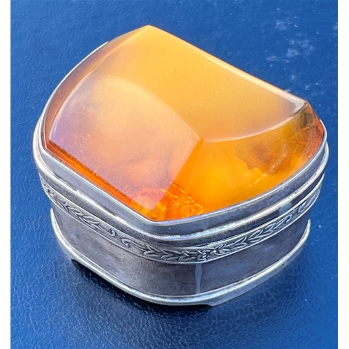 115 - AMBER TOPPED SILVER TRINKET BOX standing 4.5cm tall x 5.3cm long, with a band of embossed floral and... 