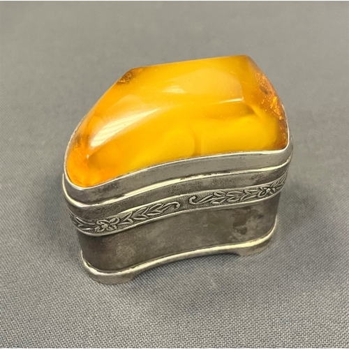 115 - AMBER TOPPED SILVER TRINKET BOX standing 4.5cm tall x 5.3cm long, with a band of embossed floral and... 