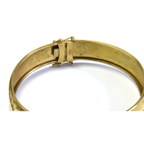 27 - 9CT GOLD HINGED BANGLE 13.1mm wide with scroll and bright cut engraving to front, hinge to one side,... 