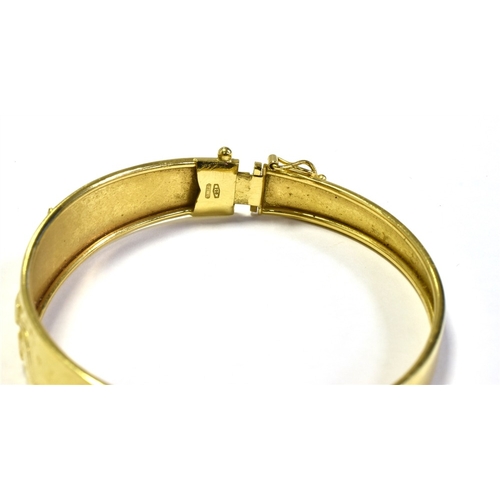 65 - 18CT GOLD ENGRAVED BANGLE 12.9mm foliate and scroll engraved front, hinge to one side and plain back... 