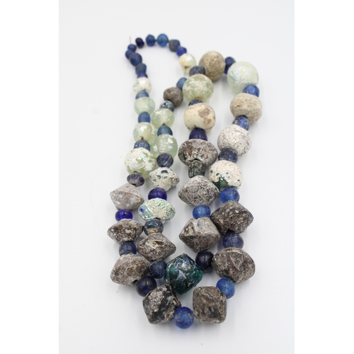 284 - Ancient Roman glass necklace or bead showcasing a captivating patina.

Roughly 35cm long