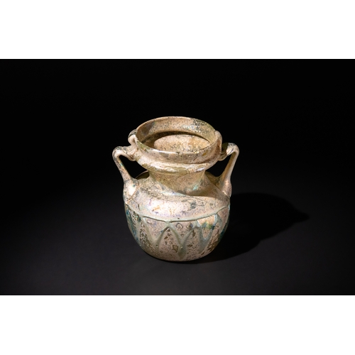 105 - A Roman Beige & Blue Glass Twin Handled Jar, 3rd–4th century A.D., Decorated with Zigzag Patterns.

... 