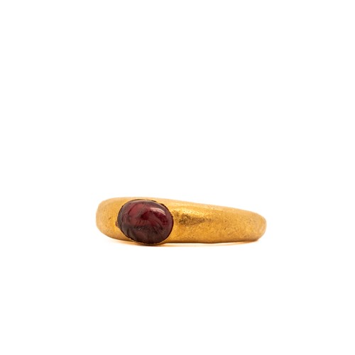 14 - A Roman Gold Hollow Ring with Garnet Cabochon.

This ring features a smooth, oval garnet gemstone se... 