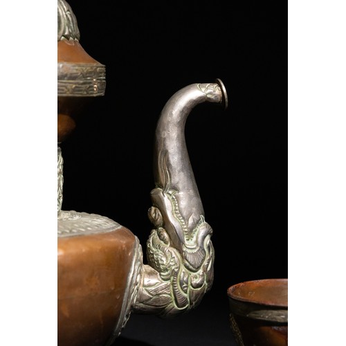 319 - **NO RESERVE**

A Tibetan Silver and Copper Dragon-Handled Tea Pot with Cup.

An ornamented Tibetan ... 