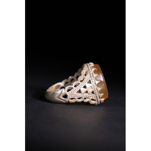 52 - An Islamic Silver Ring with Inscribed Honey Agate.

A silver ring featuring an openwork triangular b... 
