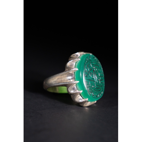53 - An Islamic Silver Ring with Inscribed Green Agate.

This silver ring features a finely carved green ... 