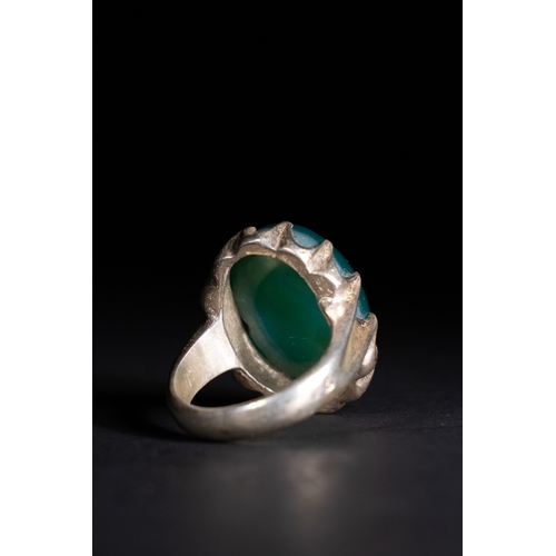 53 - An Islamic Silver Ring with Inscribed Green Agate.

This silver ring features a finely carved green ... 