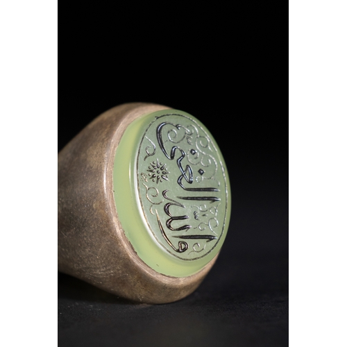 54 - An Islamic Silver Ring with Inscribed Green Agate.

A silver ring featuring a striking pale green ag... 