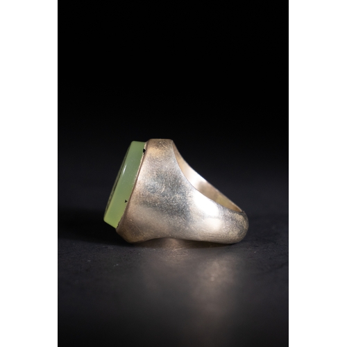 54 - An Islamic Silver Ring with Inscribed Green Agate.

A silver ring featuring a striking pale green ag... 