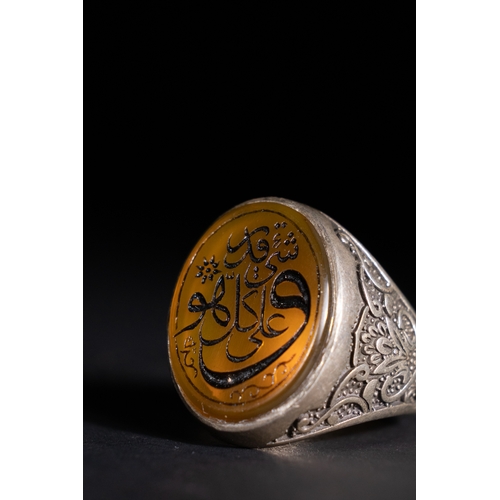55 - An Islamic Silver Ring with Amber-Toned Agate Inscription.

A silver ring featuring an amber-toned a... 