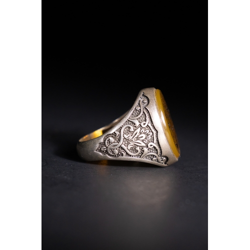 55 - An Islamic Silver Ring with Amber-Toned Agate Inscription.

A silver ring featuring an amber-toned a... 