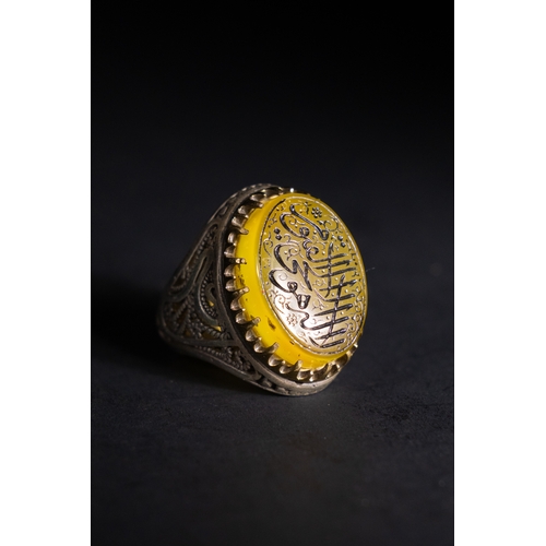 56 - An Islamic Silver Ring with Inscribed Yellow Agate.

A silver ring featuring a rounded oval yellow a... 