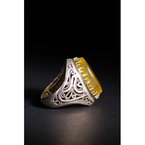 56 - An Islamic Silver Ring with Inscribed Yellow Agate.

A silver ring featuring a rounded oval yellow a... 